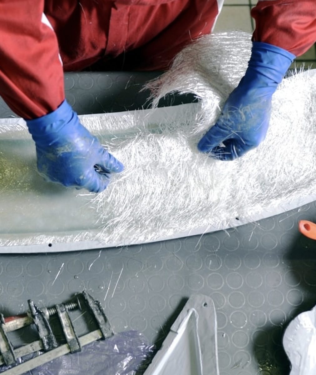 Technician laying fiberglass cloth during a hull repair