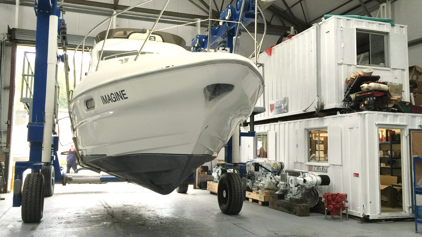 Boat lifted on a marine travel lift inside the shop