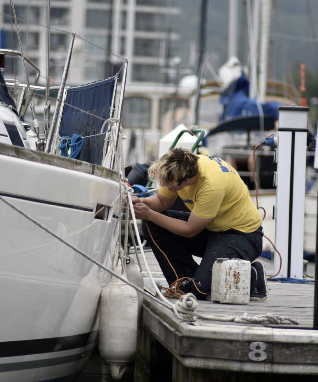 Technician assessing boat damage for an insurance claim at a marina